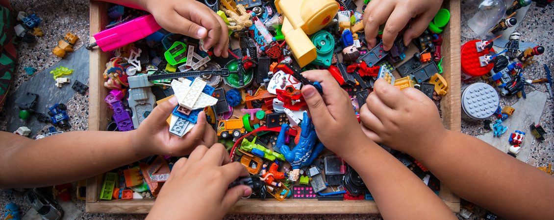 The hands of many children who are playing toys together.